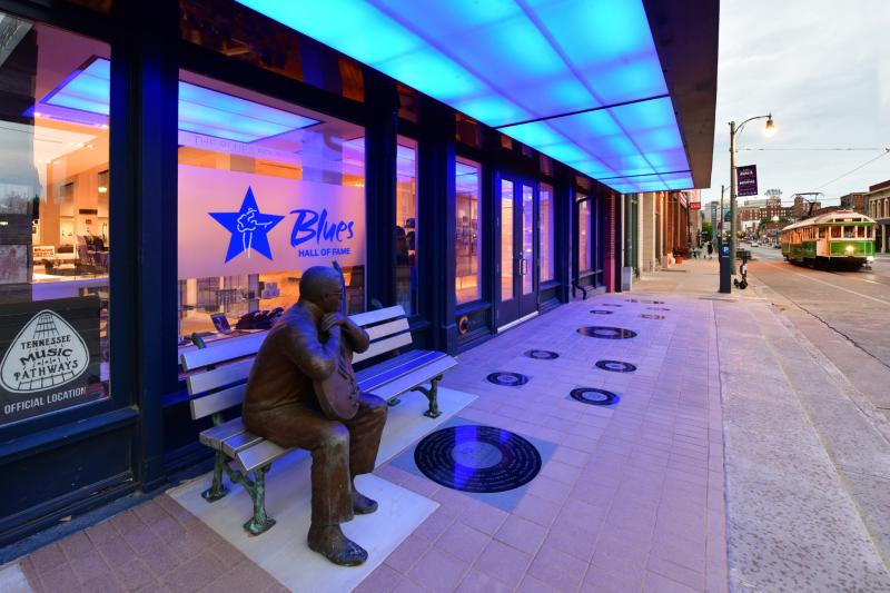 view of Blues Hall of Fame exterior with blue lights and Little Milton Statue