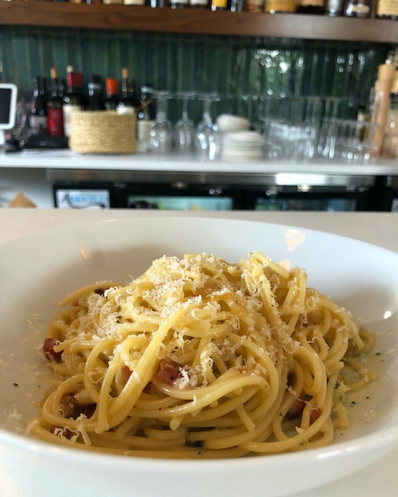 bowl of pasta carbonara sitting on white countertop
