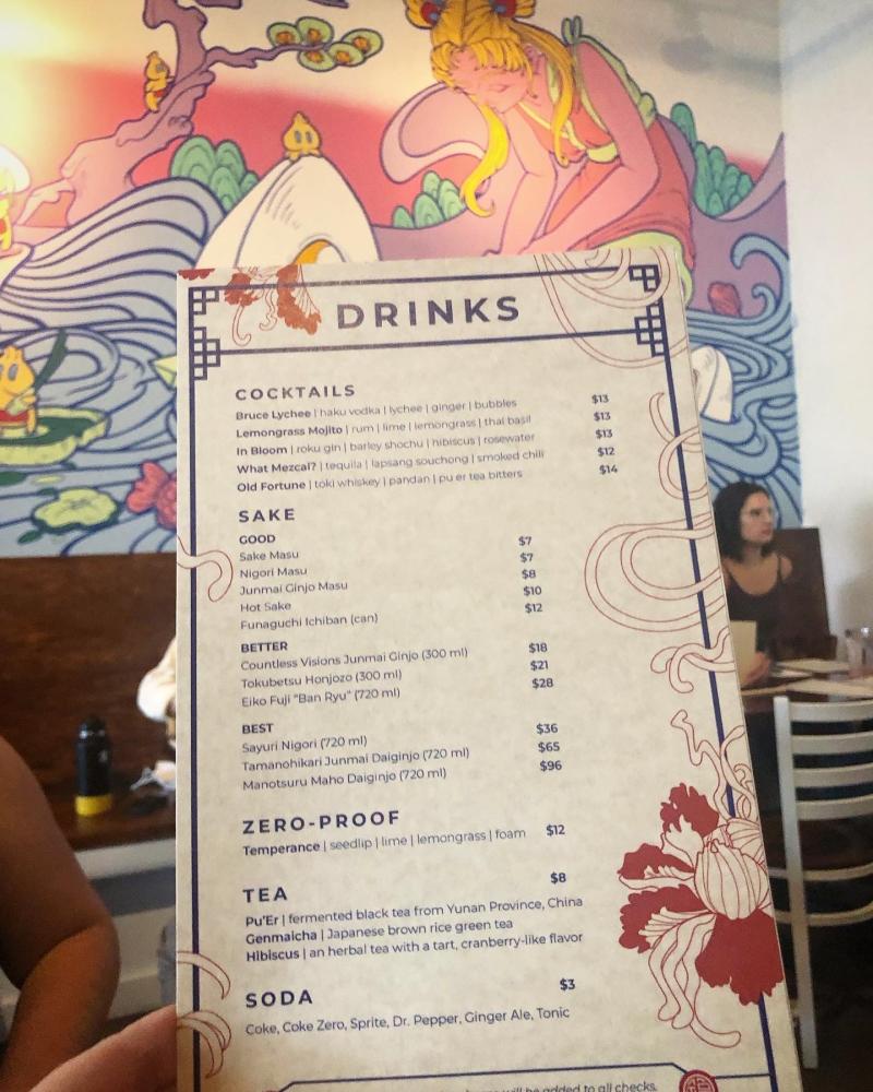 menu for cocktails and sake at restaurant with Asian style mural in the background