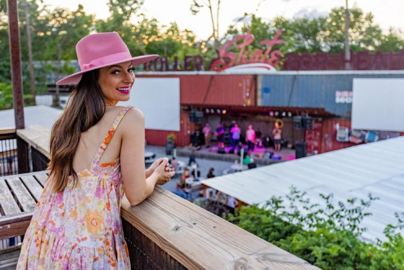 girl in hat standing on balcony in front of the railgarten stage
