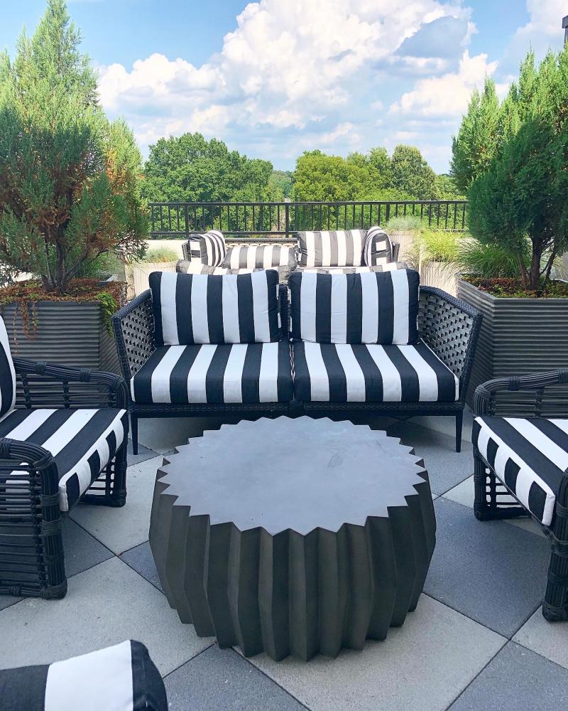 striped outdoor seats surrounded by shrubs on. rooftop