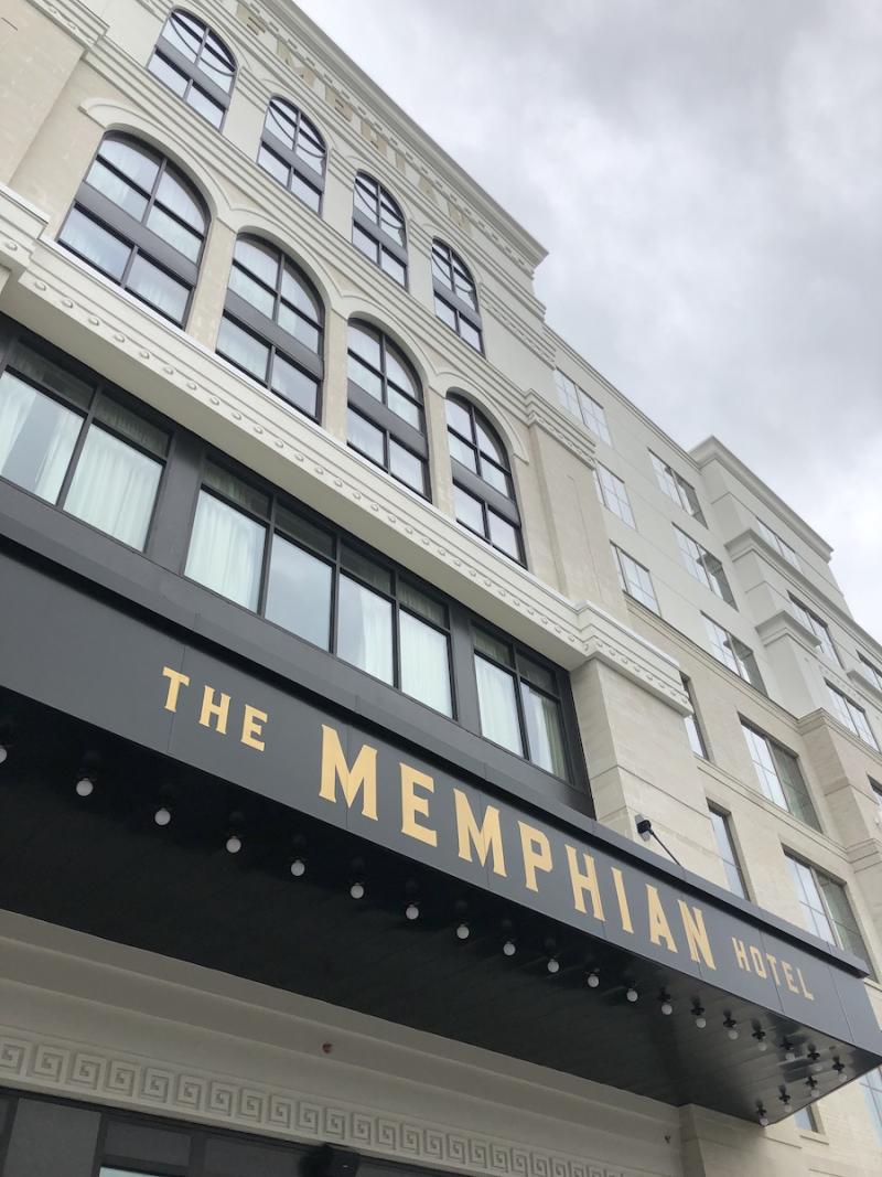 white hotel building looking up with The Memphian sign