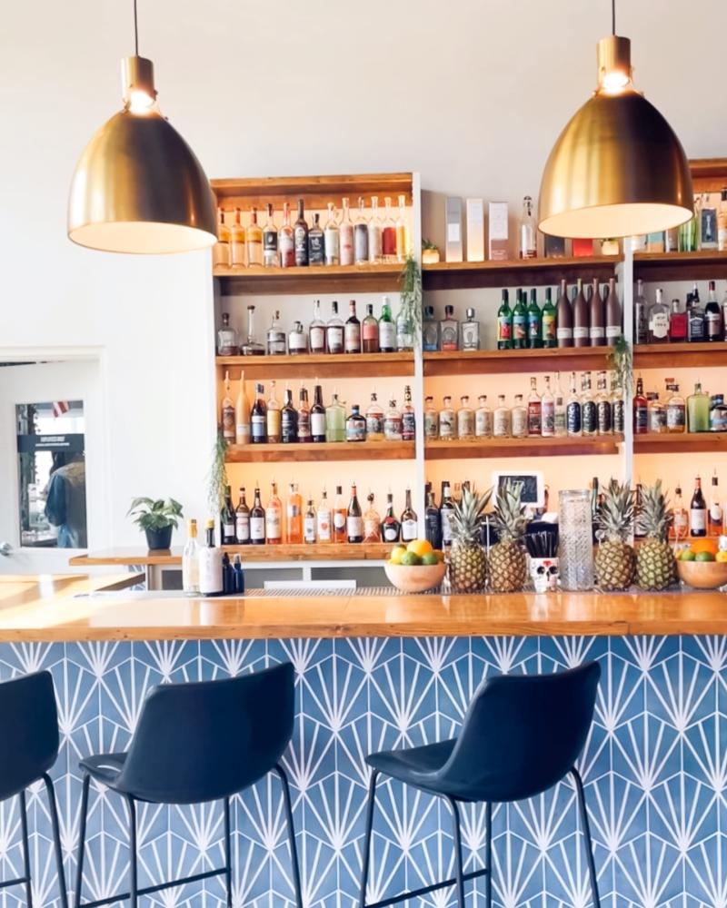 stylish bar with wood shelves, blue wallpaper under bar, bronze lamps