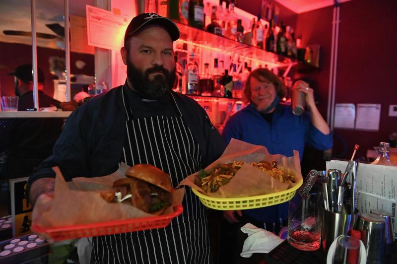 chef holding burger and bites at bar