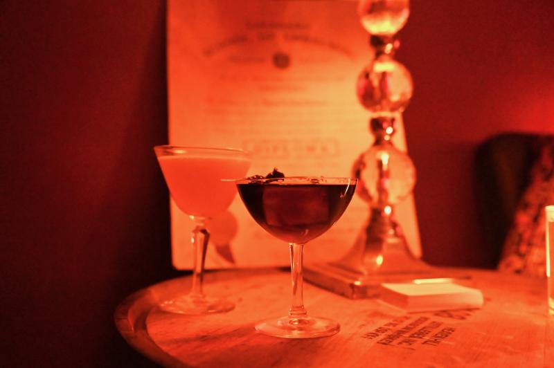 two craft cocktails on an antique table in soft sepia lighting
