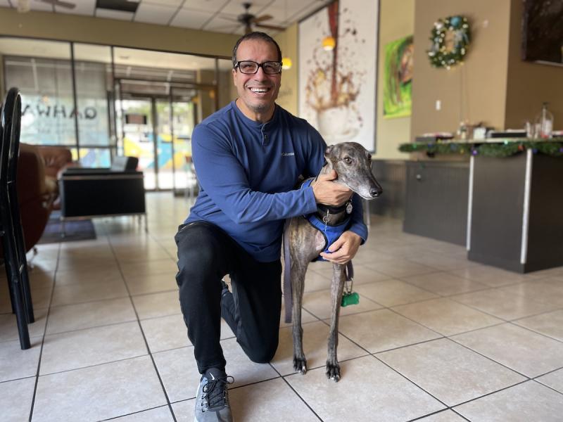 man in blue shirt kneeling with a dog