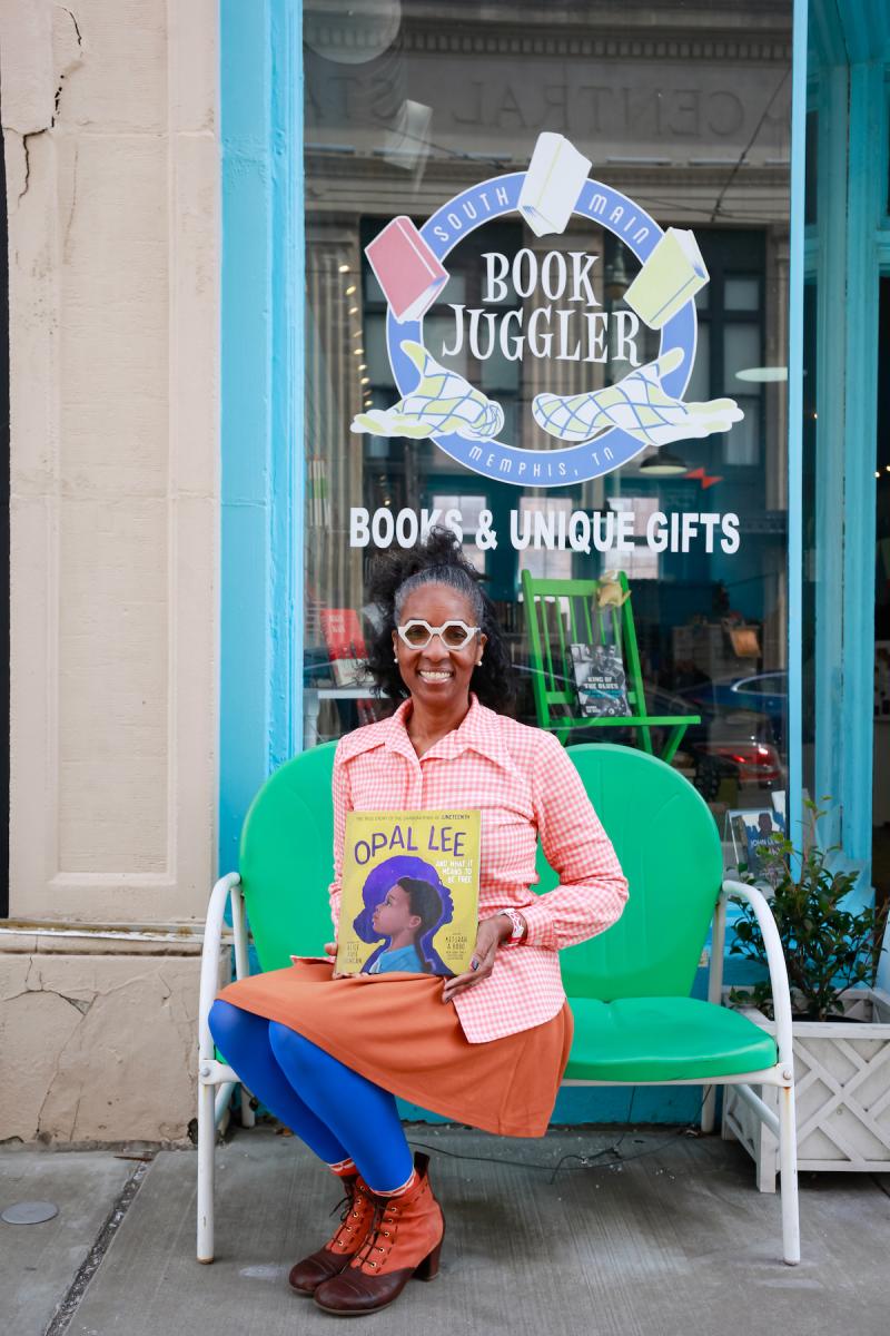 woman sitting in front of book store holding children's book