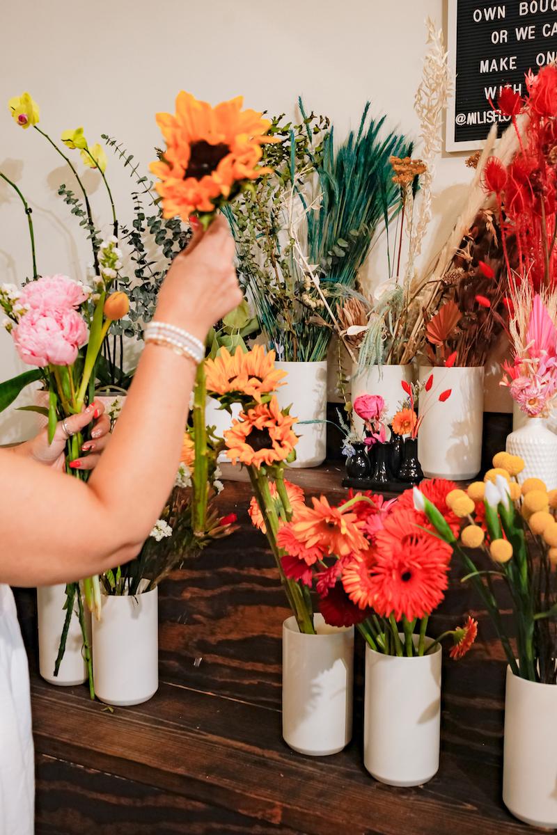 hand reaching for sunflower in bouquet wall
