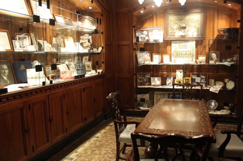 small room with dining table, wooden panels, and shelves of photos and papers