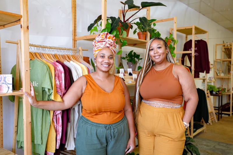 Two women in warm toned tops standing in a plant and gift shop