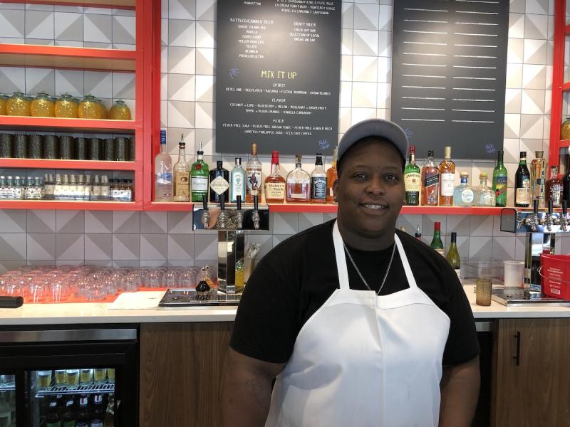 chef in white apron standing in front of bar