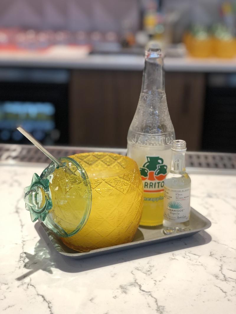 yellow glass pinapple shaped glass with bottle of soda and airplane bottle of tequila