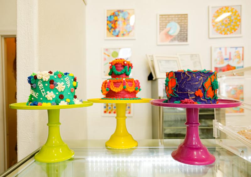three colorful cakes on colorful stands