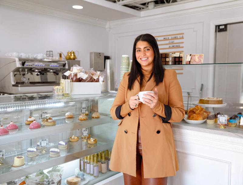Owner of 17 Berkshire stands in front of treats display case smiling for photo