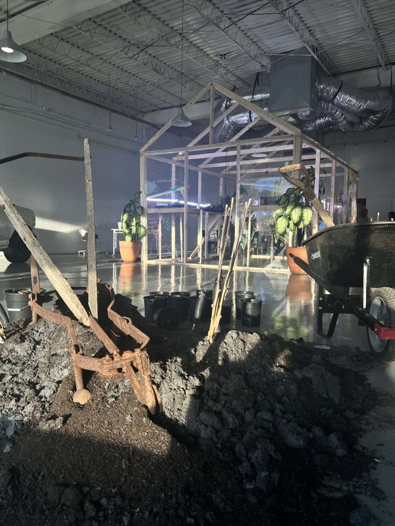 Photo of inside tone showing the brick x brick activation. There is first on the ground with shovels and the outline of a greenhouse in the background