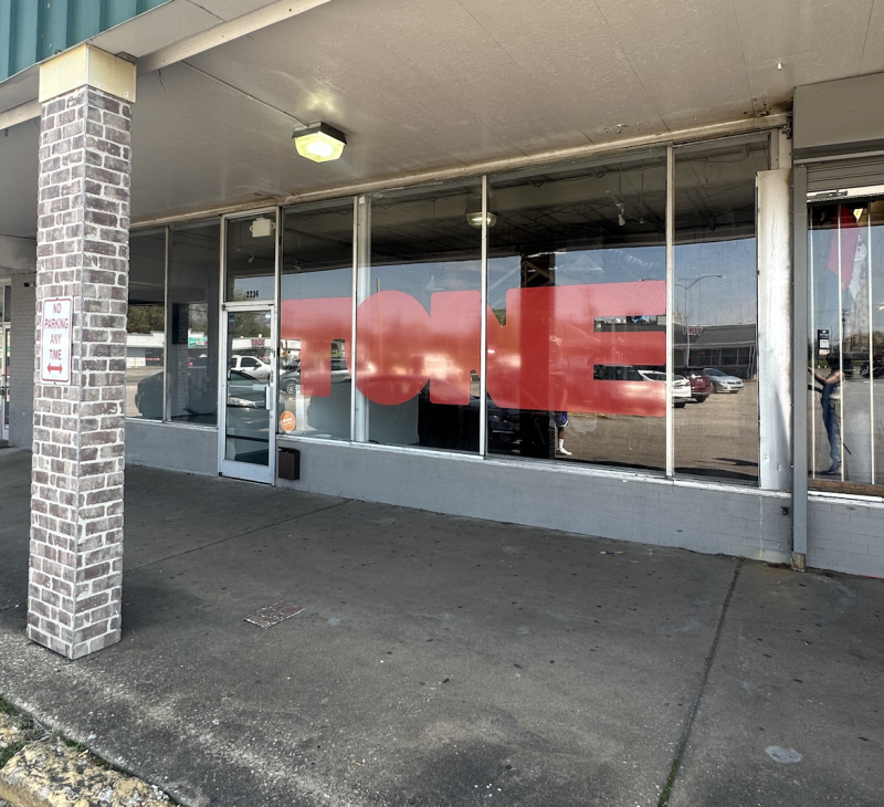 exterior photo of TONE. strip mall look with big red letters on glass windows saying TONE