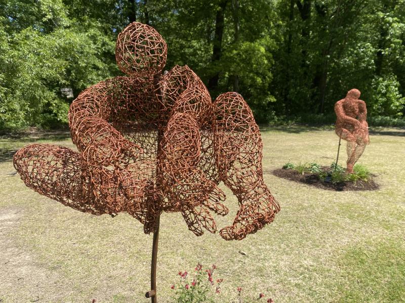 wired man sculpture with legs up in jumping toe touch