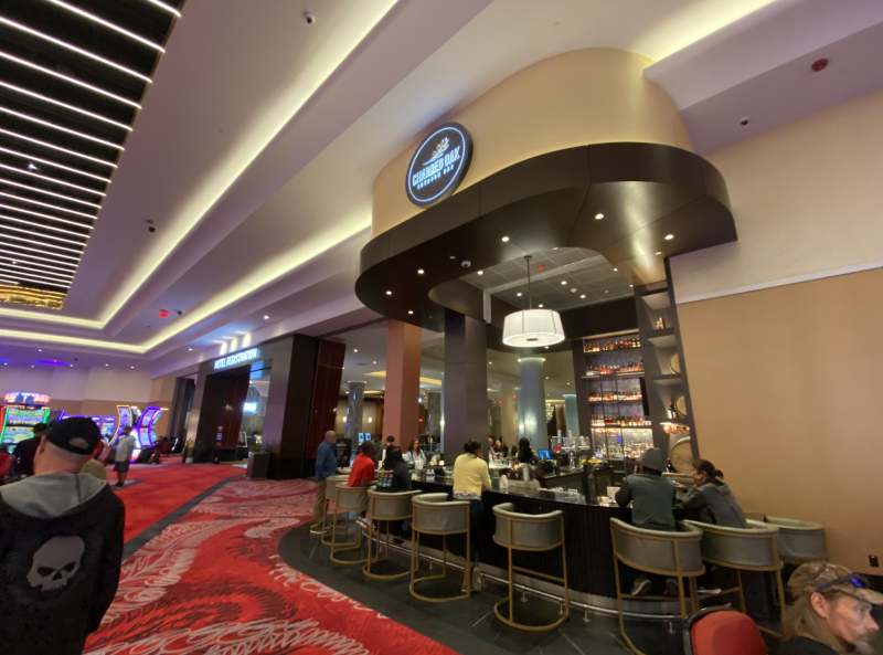 charred oak bar inside casino with big chairs wrapped around corner bar