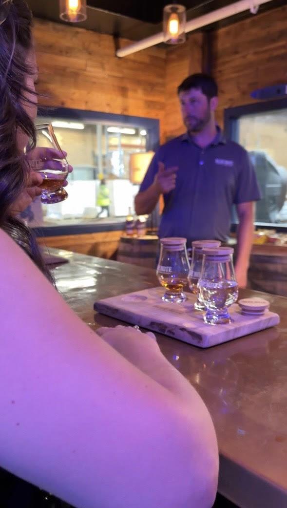 woman takes a sip out of bourbon tasting glass while bartender explains drink