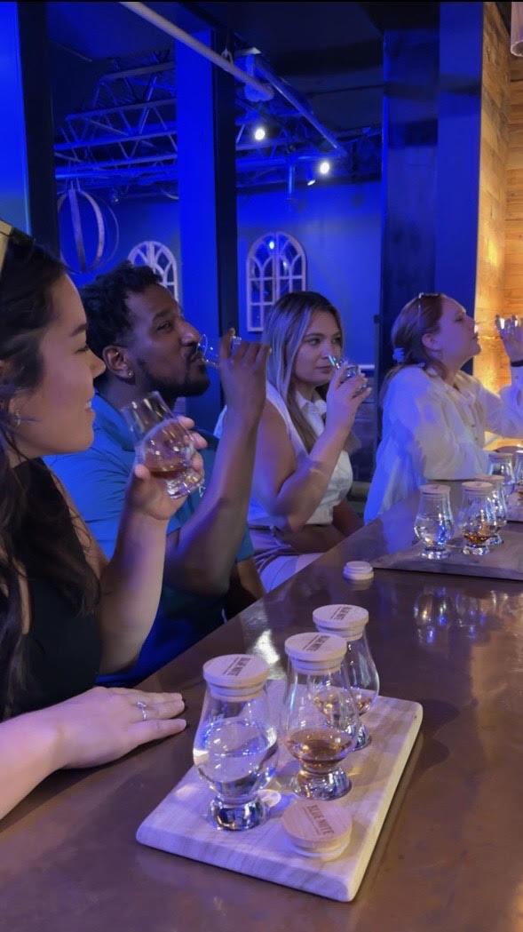 four people sitting at bar with bourbon tasting boards