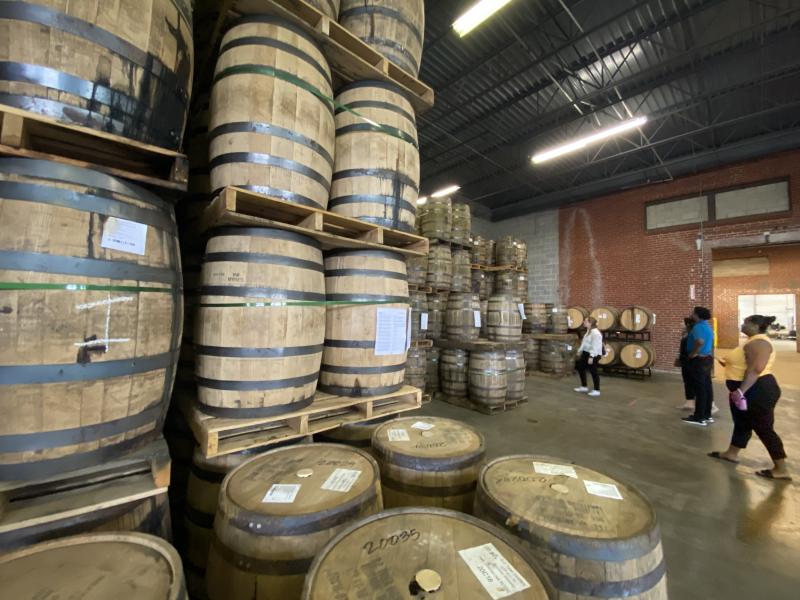 bourbon barrels stacked on top of each other in production facility with people on tour in background