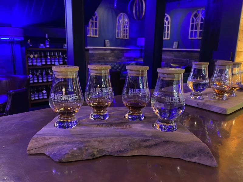 four bourbon tasting glasses on a wooden plate