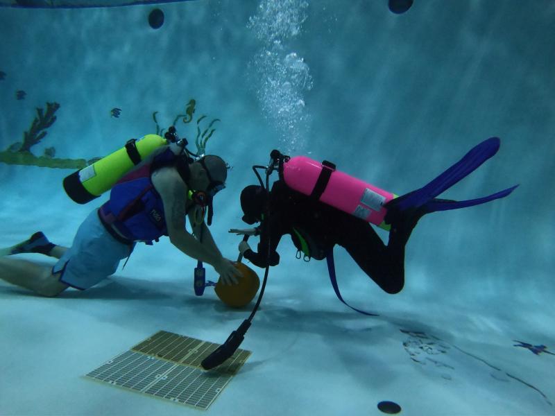 scuba divers training in pool with ball
