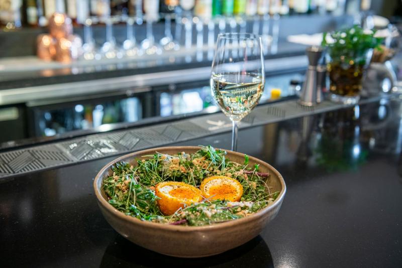 scottish eggs sitting in bowl with glass of wine on bar