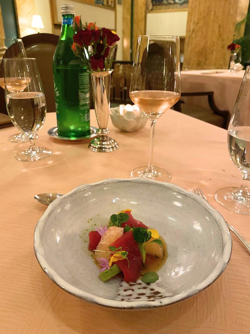 tuna crudo in dish with table and wine visible