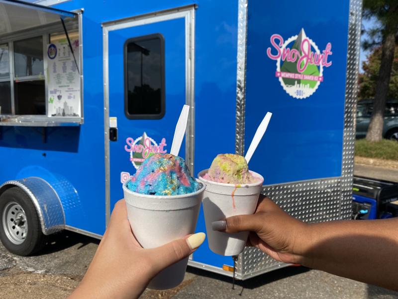 sno cones held up with trailer in background