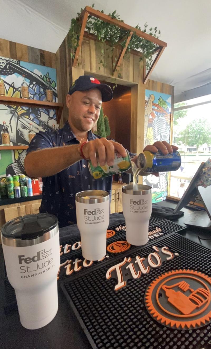 bartender makes cocktail pouring into tumbler