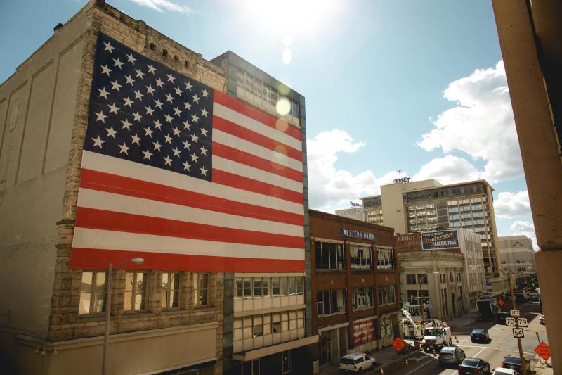 very large American flag hangs on side of building