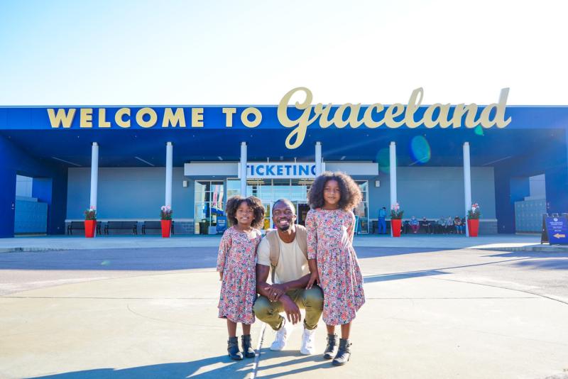 dad poses with daughter in front of welcome to Graceland sign