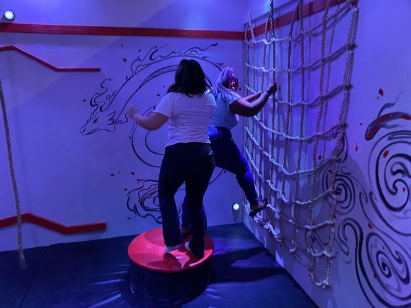 two women climb and play in ninja themed training room