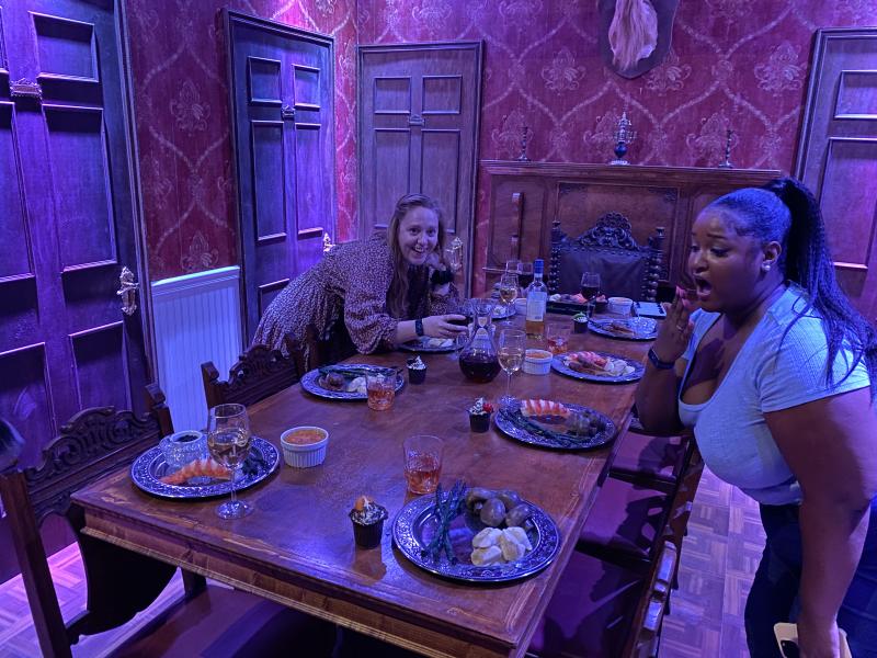 two girls pose with murder mystery table