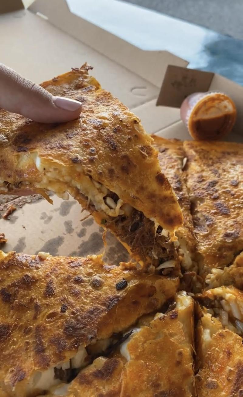 pulling a slice of the birria pizza