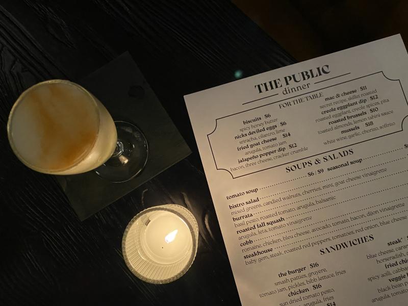 cocktail next to candle and dining menu