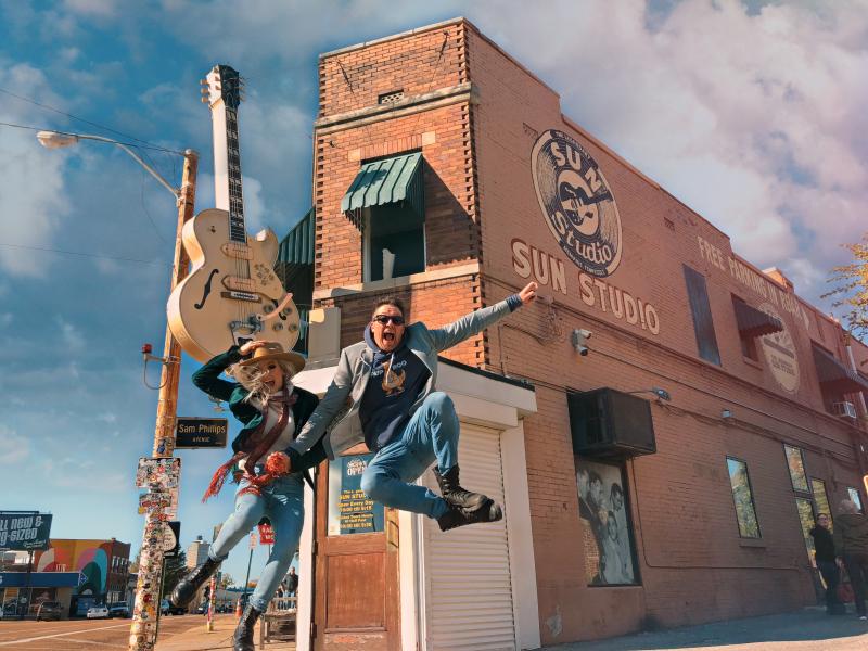 two people jump in the air in front of sun studio