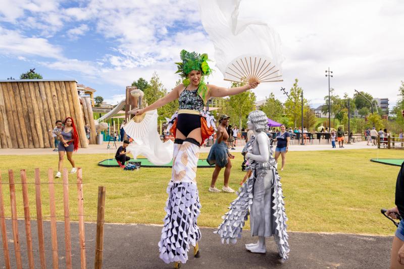 Tom Lee Park lady on stilts with colorful outfit on at the park