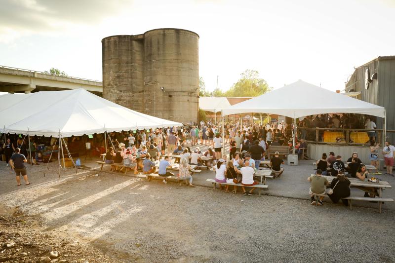 People gathered at picnic tables and under tents at Taste the Rarity beer festival at Wiseacre Brewing Co.