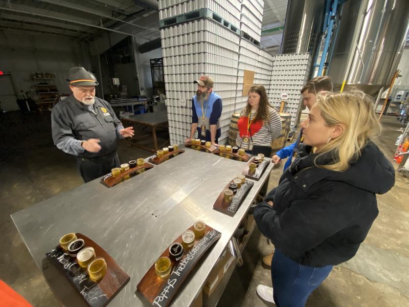people stand around table with flights of beer