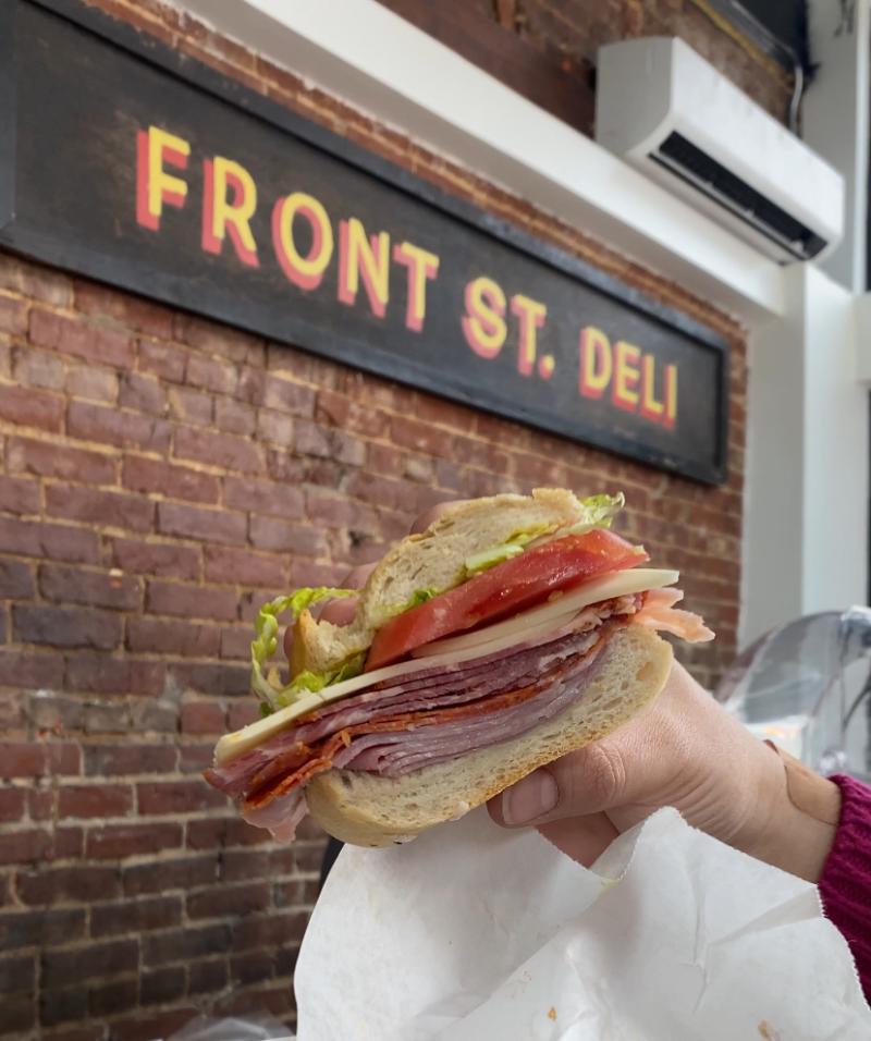 italiano sub held up to sign of Front St Deli