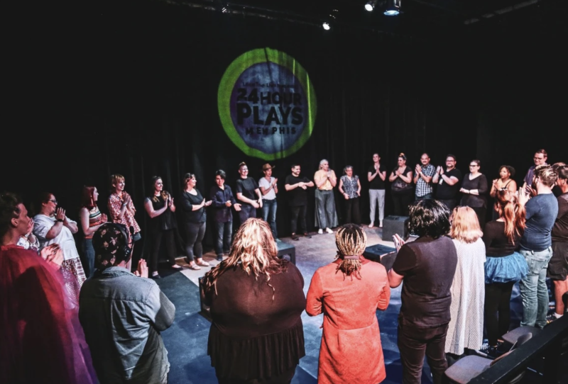 theatre participants stand in circle on stage