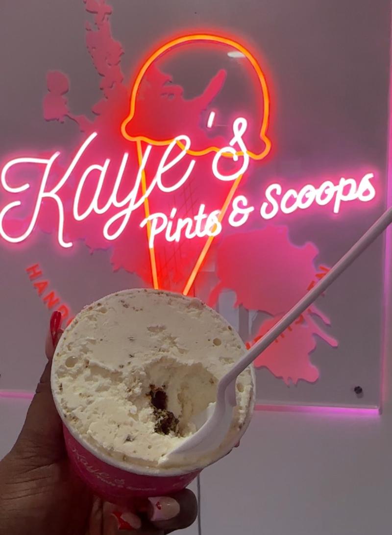 holding open ice cream with missing bite in front of a neon sign