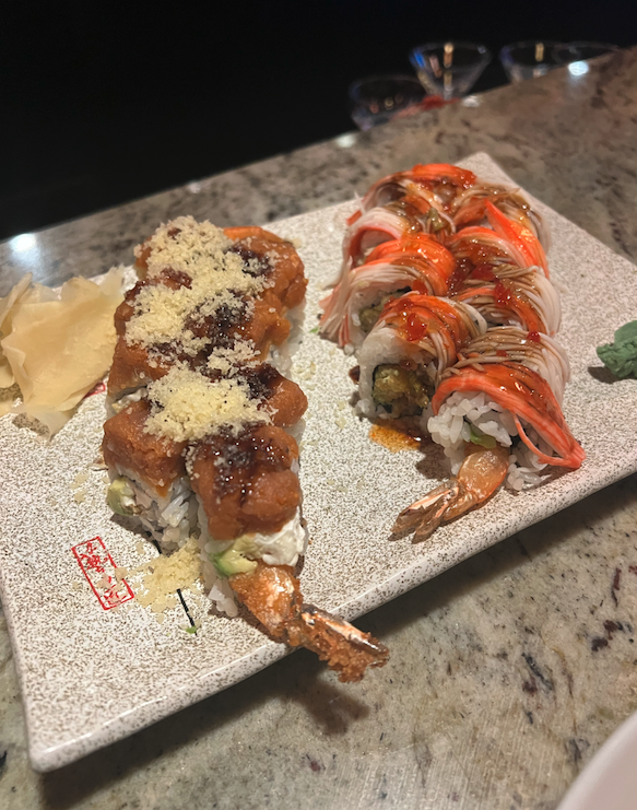 two sushi rolls loaded with toppings