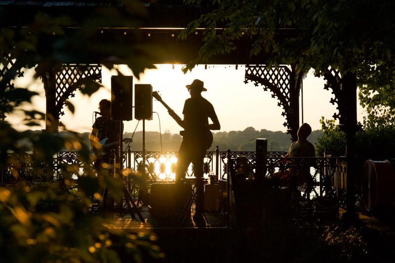 band plays on gazebo with sunset background