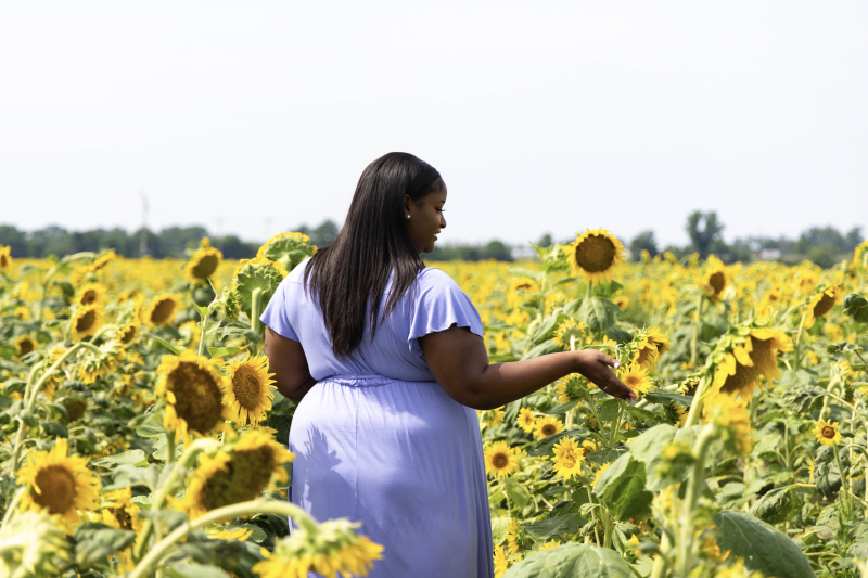 woman walks through sunflowers