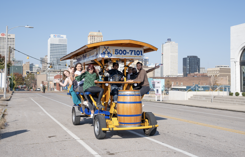 group of people smiling for photo while riding on peddle tavern