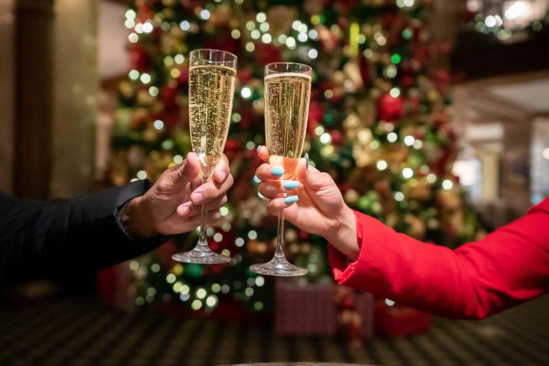 woman and man holding champagne glasses by Christmas tree
