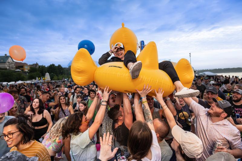 man rides on giant duck floatie crowdsurfing at riverbeat